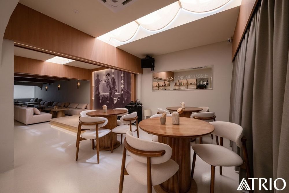 A Trio Design bar with timber tables, curved forms and skylight